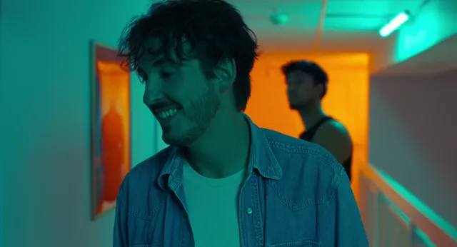 Image du court métrage Momentum : un personnage souriant dans un couloir éclairé aux néons turquoise et orange
