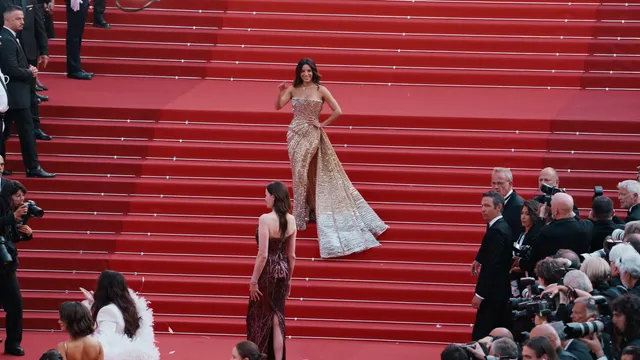 Une invitée en robe dorée seule sur les marches rouges du Palais des Festivals, filmée en plongée pendant le Festival de Cannes